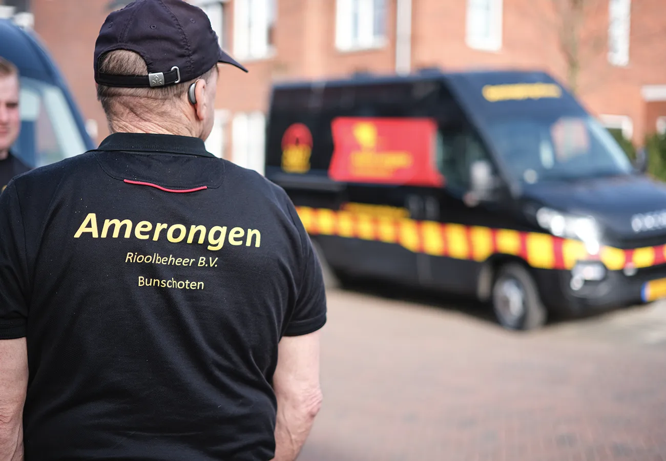 Vakman van Amerongen Rioolbeheer, specialist in het ontstoppen van een verstopte douche, bij de bedrijfsbus