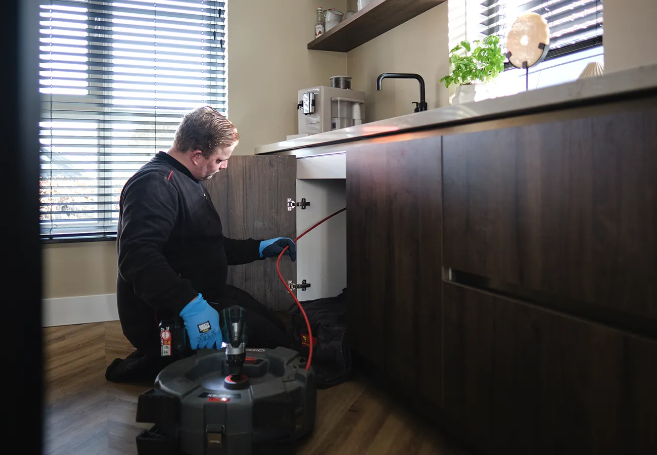 Monteur van Amerongen Rioolbeheer ontstopt een verstopte gootsteen in de keuken