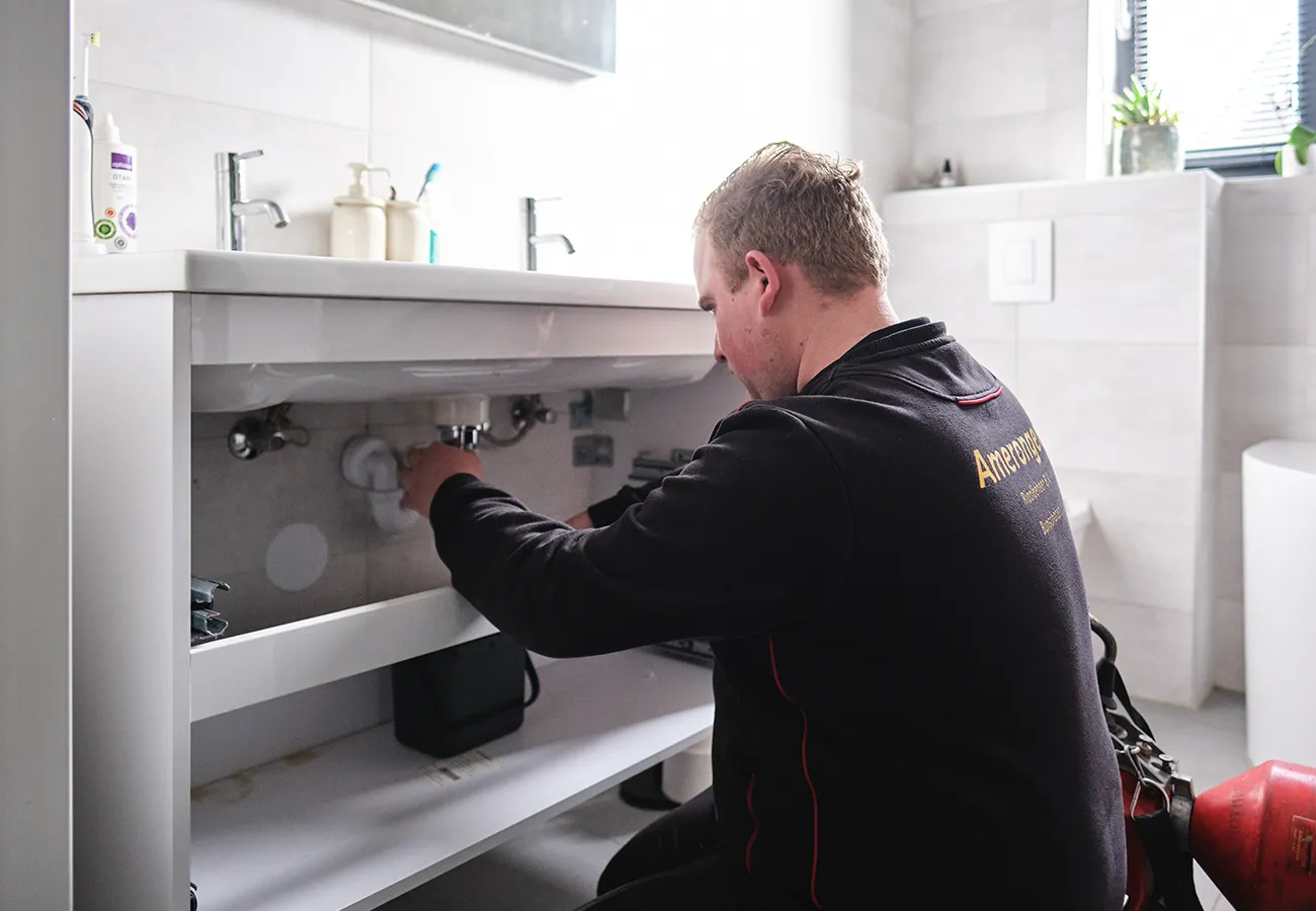 Monteur van Amerongen Rioolbeheer ontstopt de afvoer van een gootsteen in de badkamer