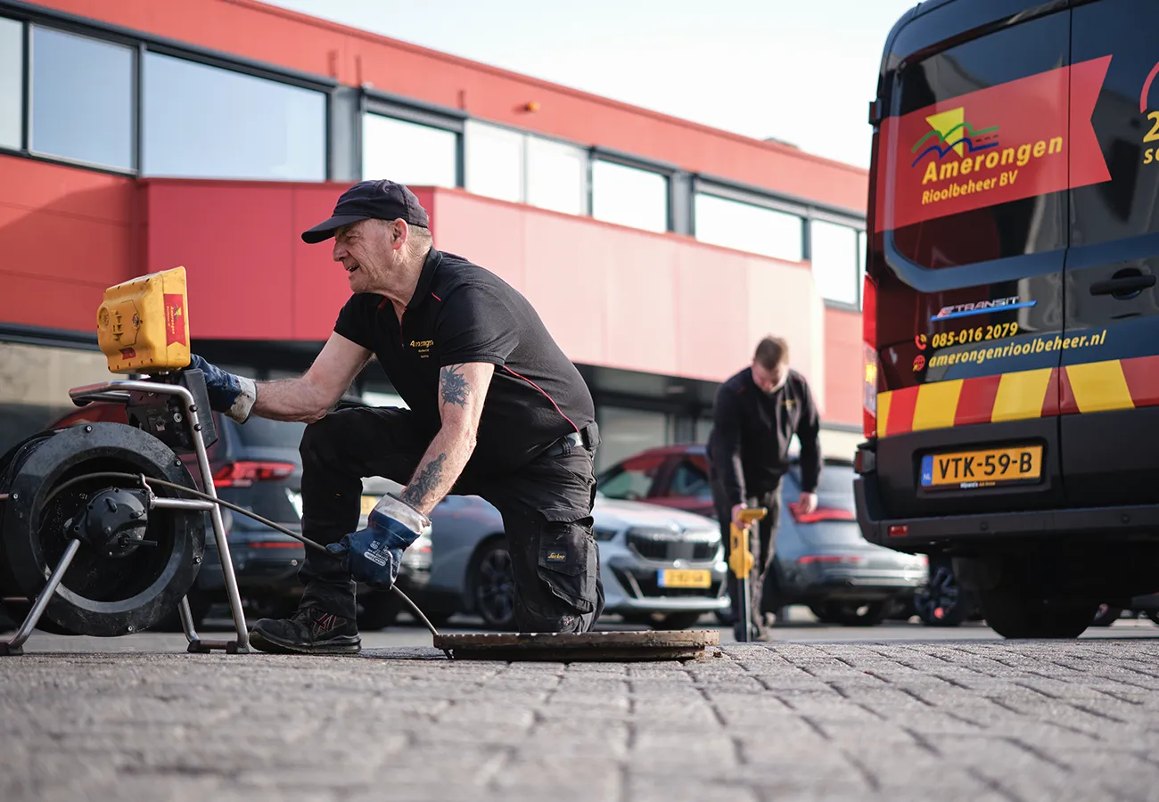 Medewerkers van Amerongen Rioolbeheer ontstoppen een verstopt riool bij een rioolput