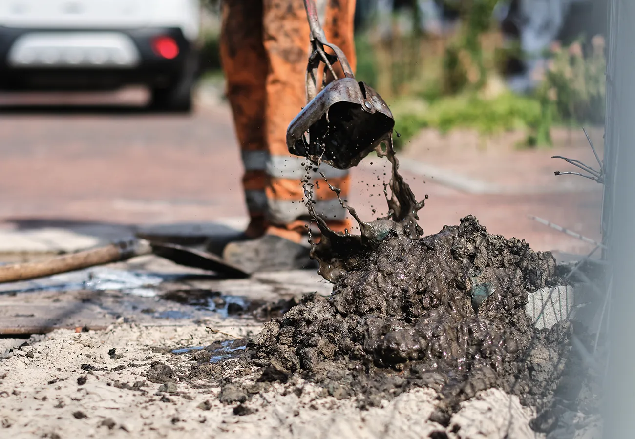 Rioolontstopping op straat waarbij slib en vuil uit de rioolput worden verwijderd