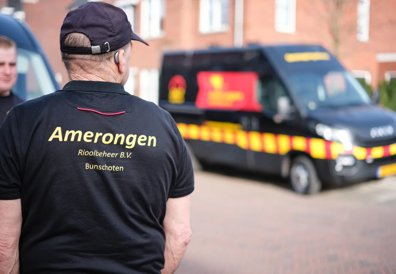 Monteur van Amerongen Rioolbeheer uit Bunschoten bij de bedrijfsbus, klaar om een verstopte douche te verhelpen