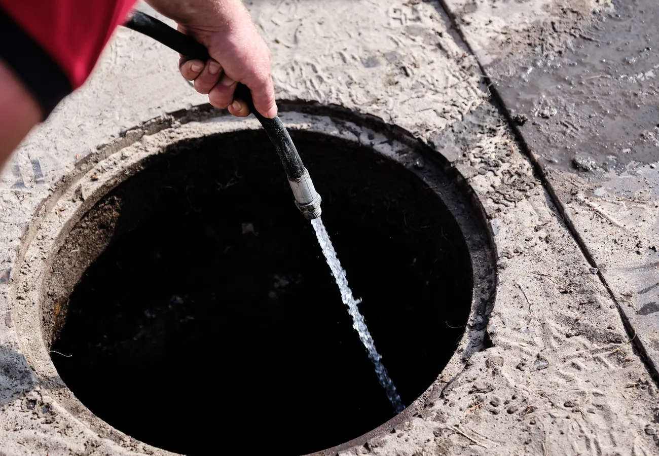 Monteur van Amerongen Rioolbeheer spuit met een hogedrukslang de rioolput schoon bij een rioolverstopping in Leusden