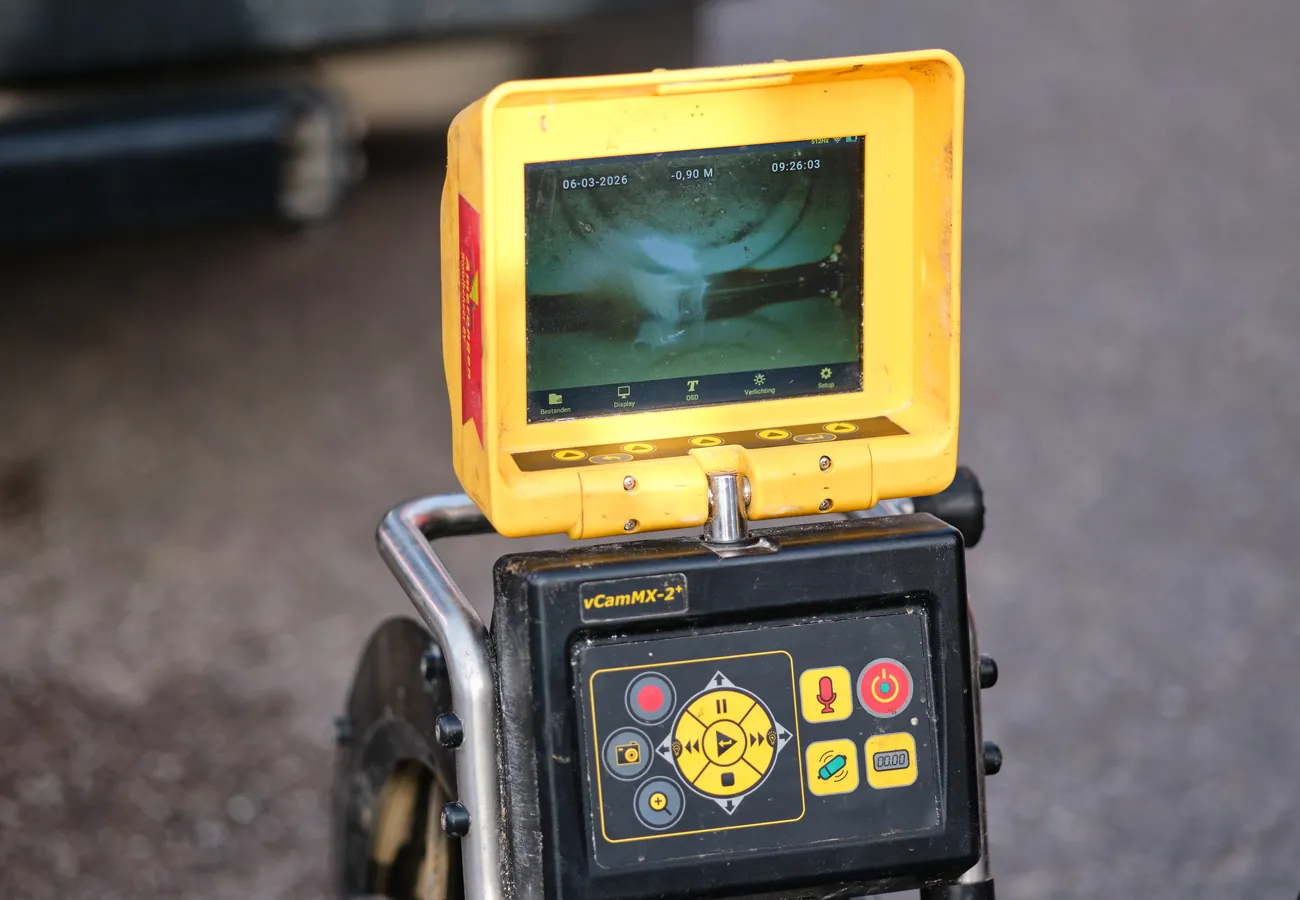Live camerabeeld op het scherm van de inspectieapparatuur tijdens een rioolinspectie, met dieptemeting van de leiding.